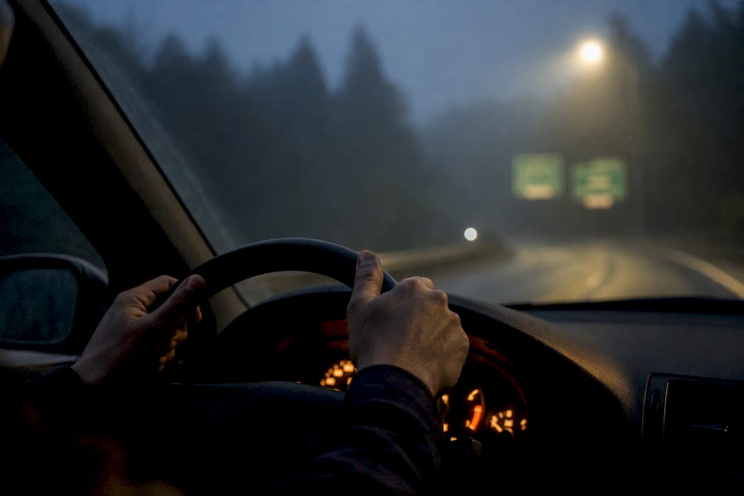 Driver’s hands on steering wheel at night