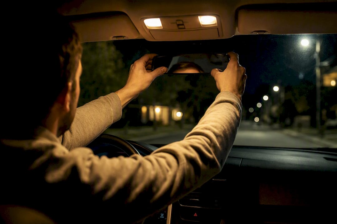 Hands adjusting headlights and mirror at night